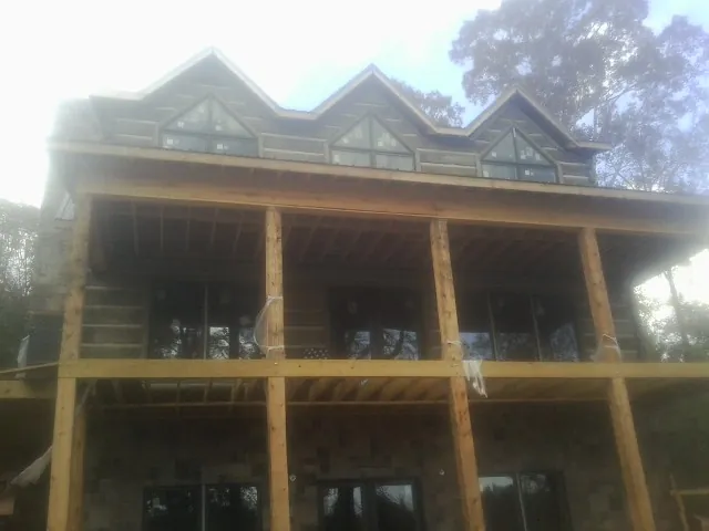 Dormers and porch framing on a large log home under construction — Roof Coating work by our crew in Glendale Springs