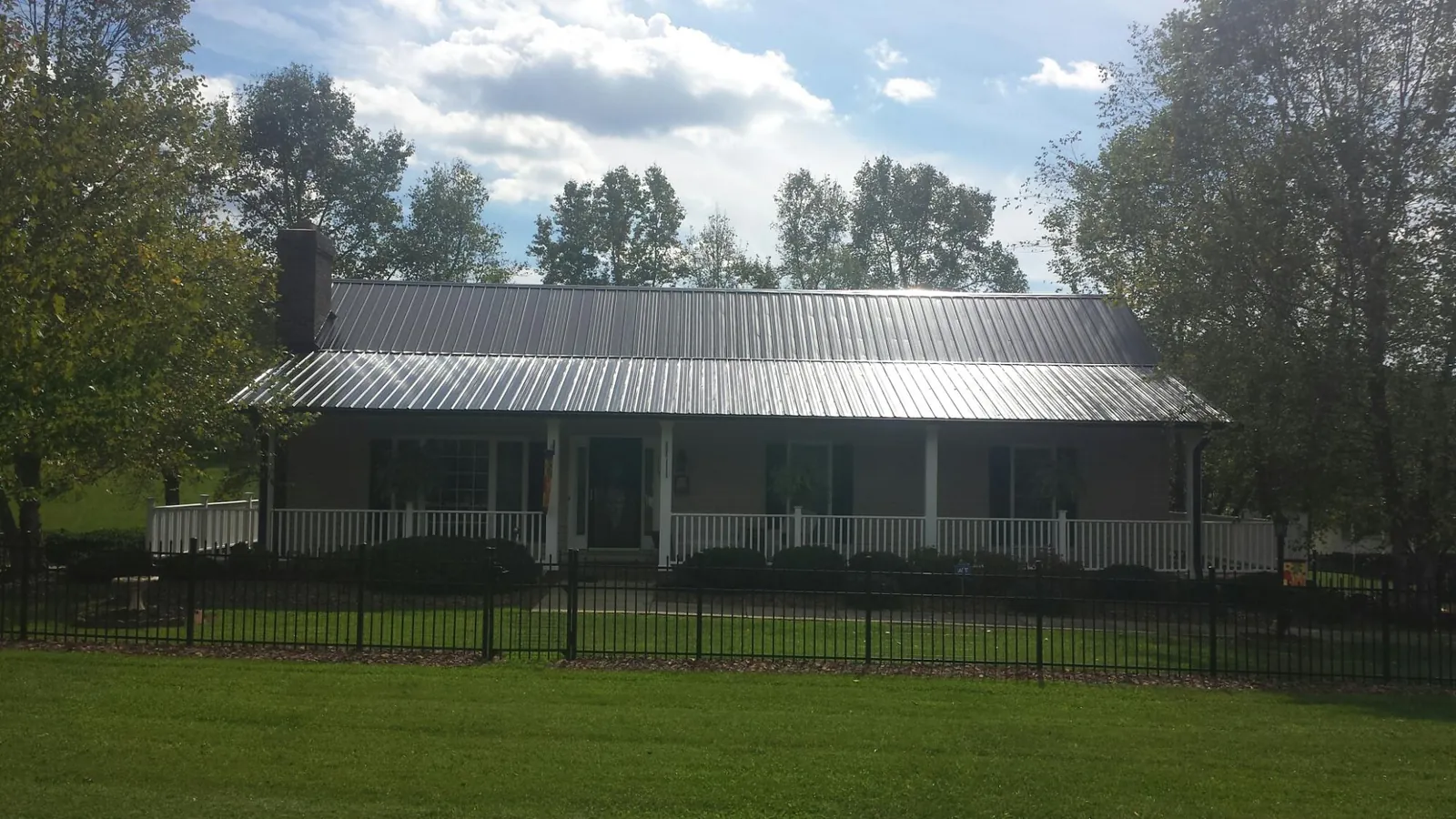 Gray metal roof on a brick ranch with a full width front porch — Gutter Guard Installation work by our crew in Glendale Springs