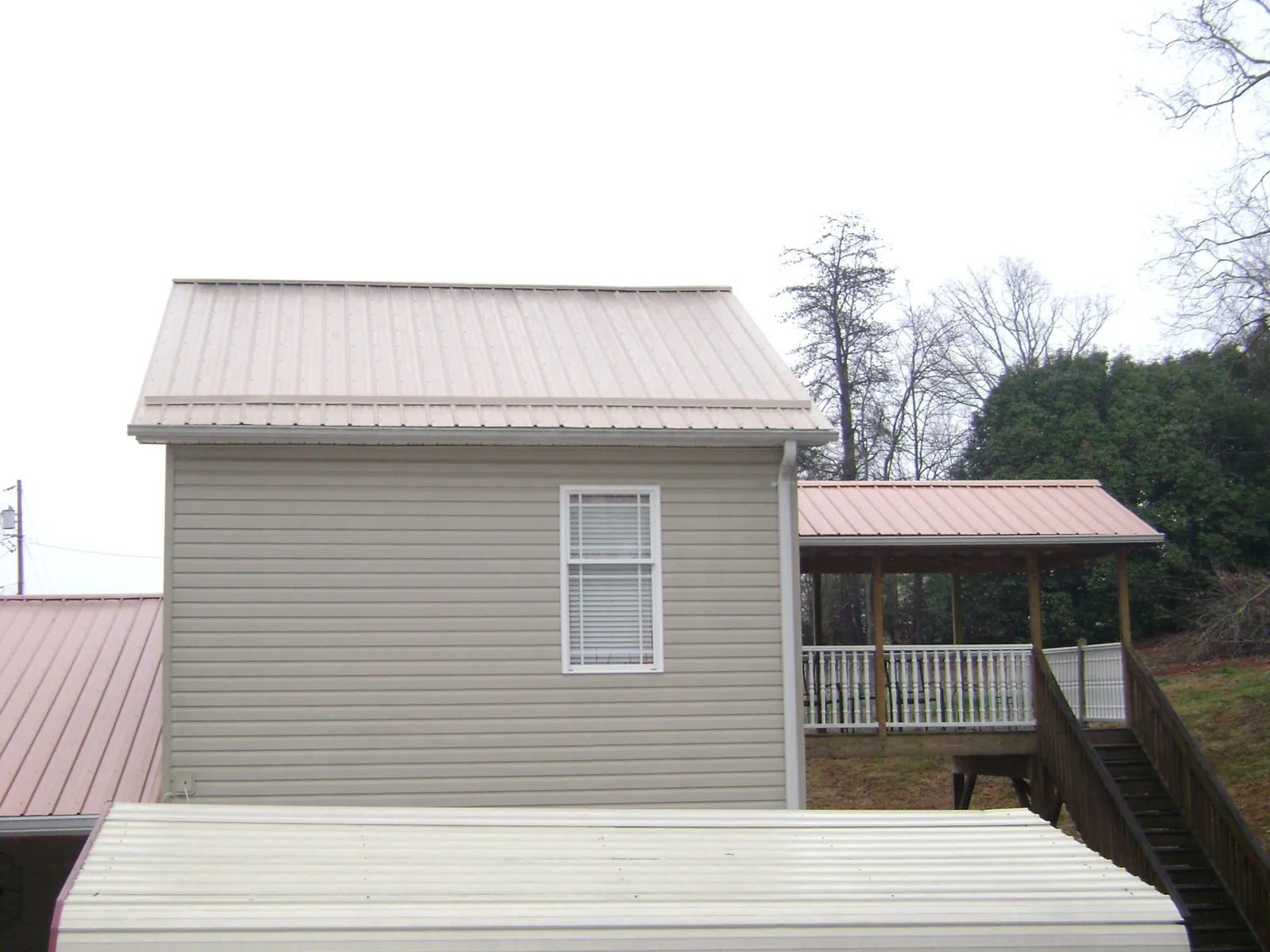 Tan metal roofs on a two story addition and attached porch, from a Roof Replacement job in Glendale Springs
