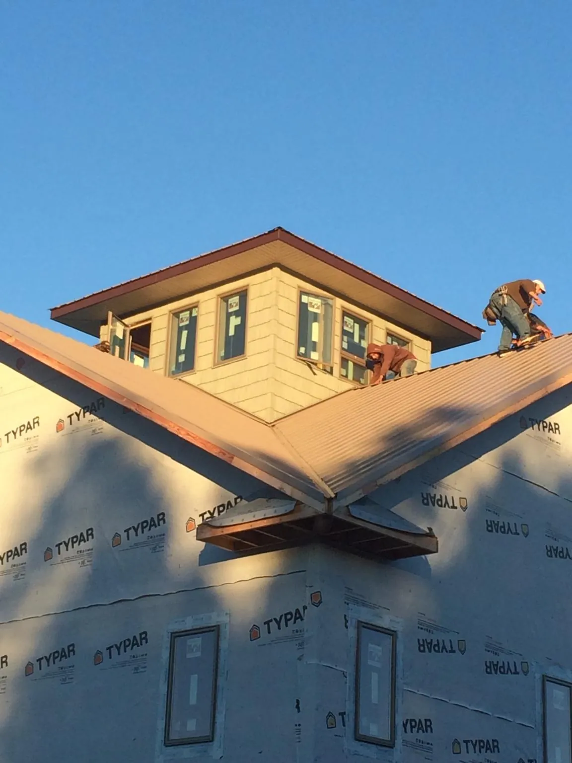 Roofers working around a rooftop cupola on a new metal roof at sunset — Roof Waterproofing in Glendale Springs by Roofing Brothers